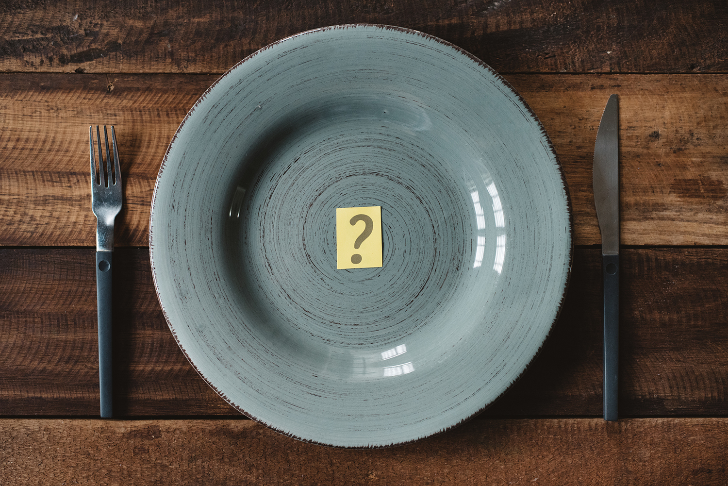 Top view of a table set with cutlery with question mark in a plate.