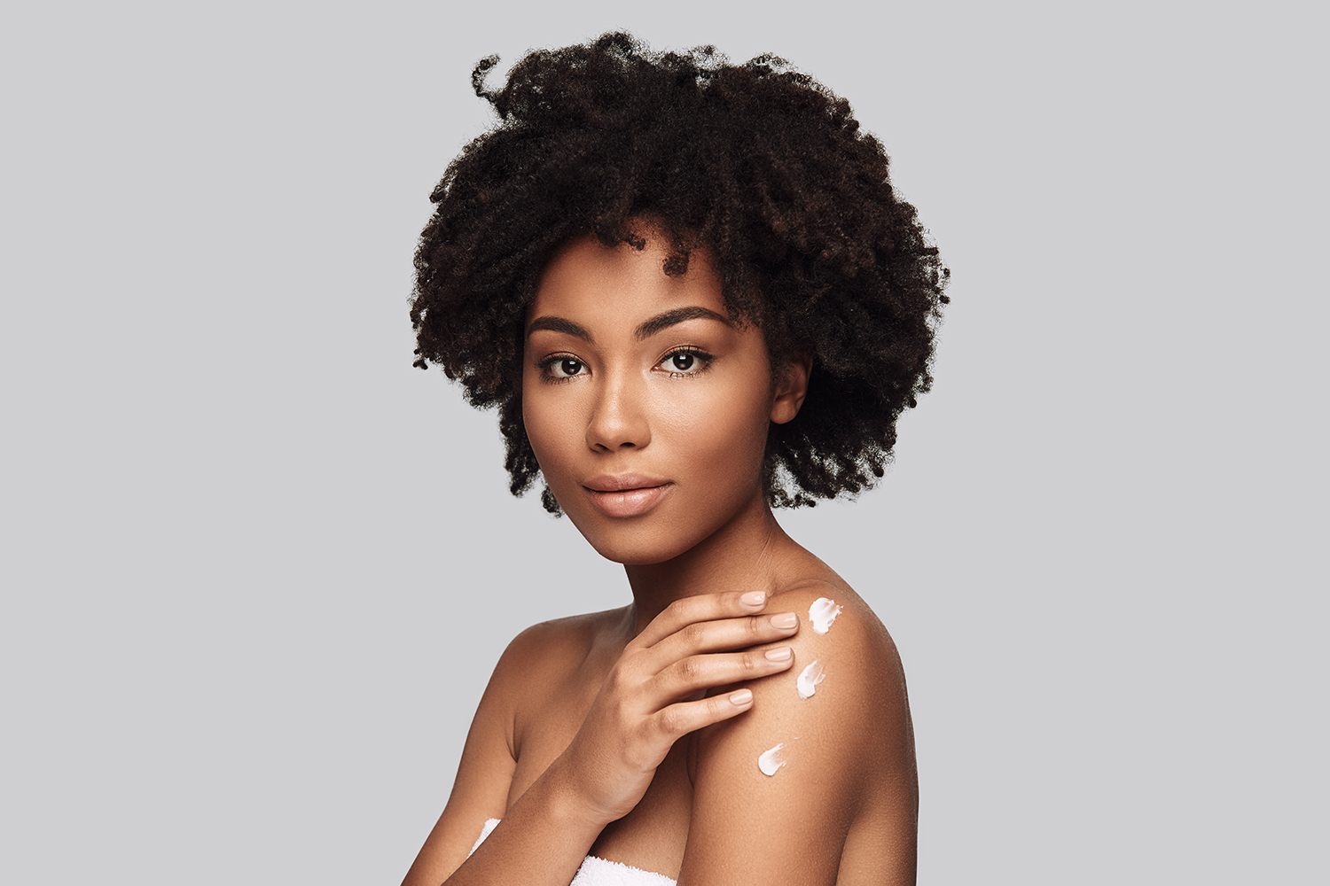 Woman rubbing lotion on her skin 