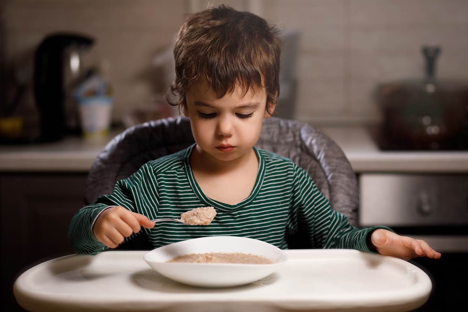a young boy on the spectrum, looking concerned about his porridge