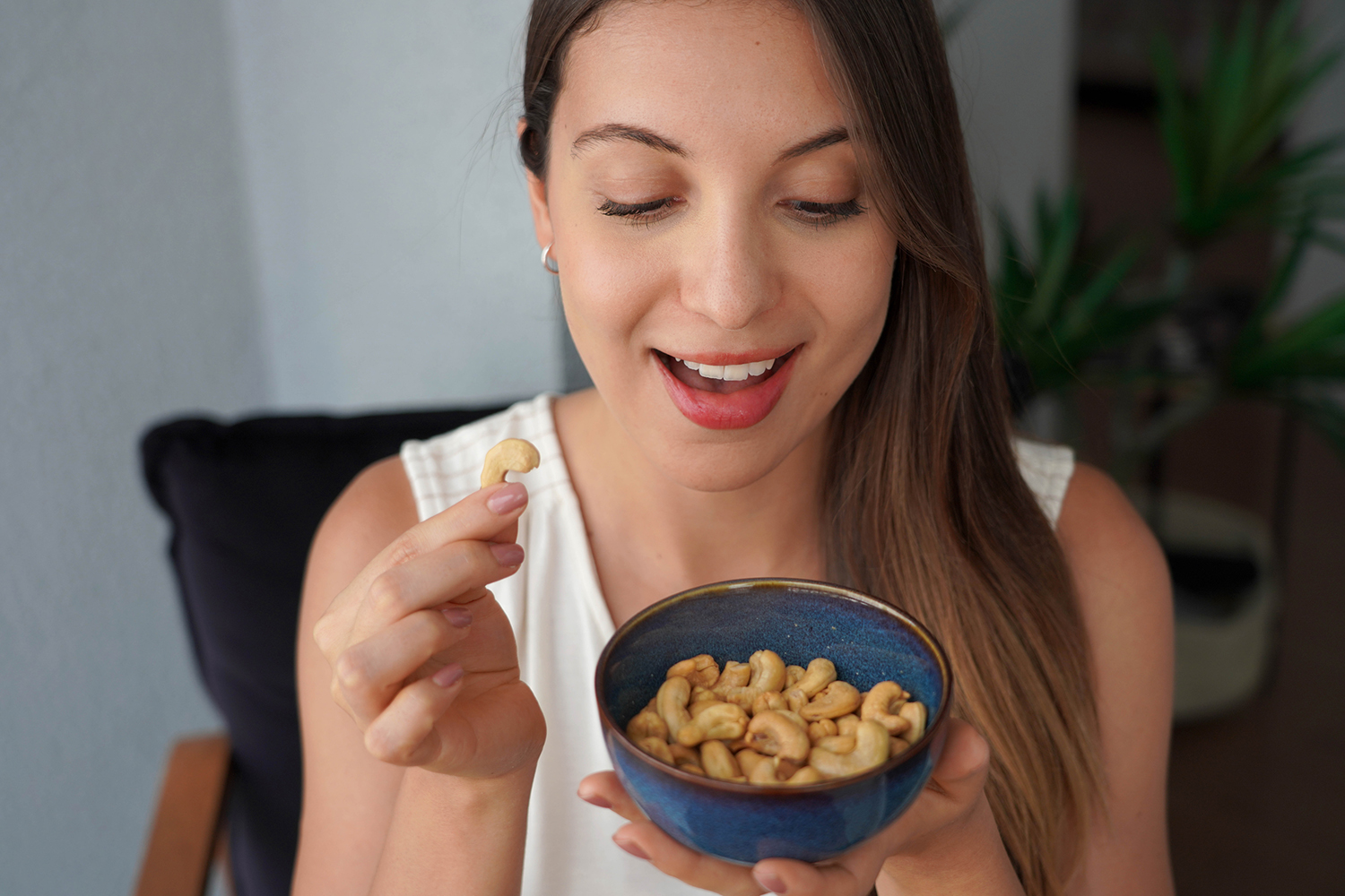 a young woman smiling while eating raw cashews