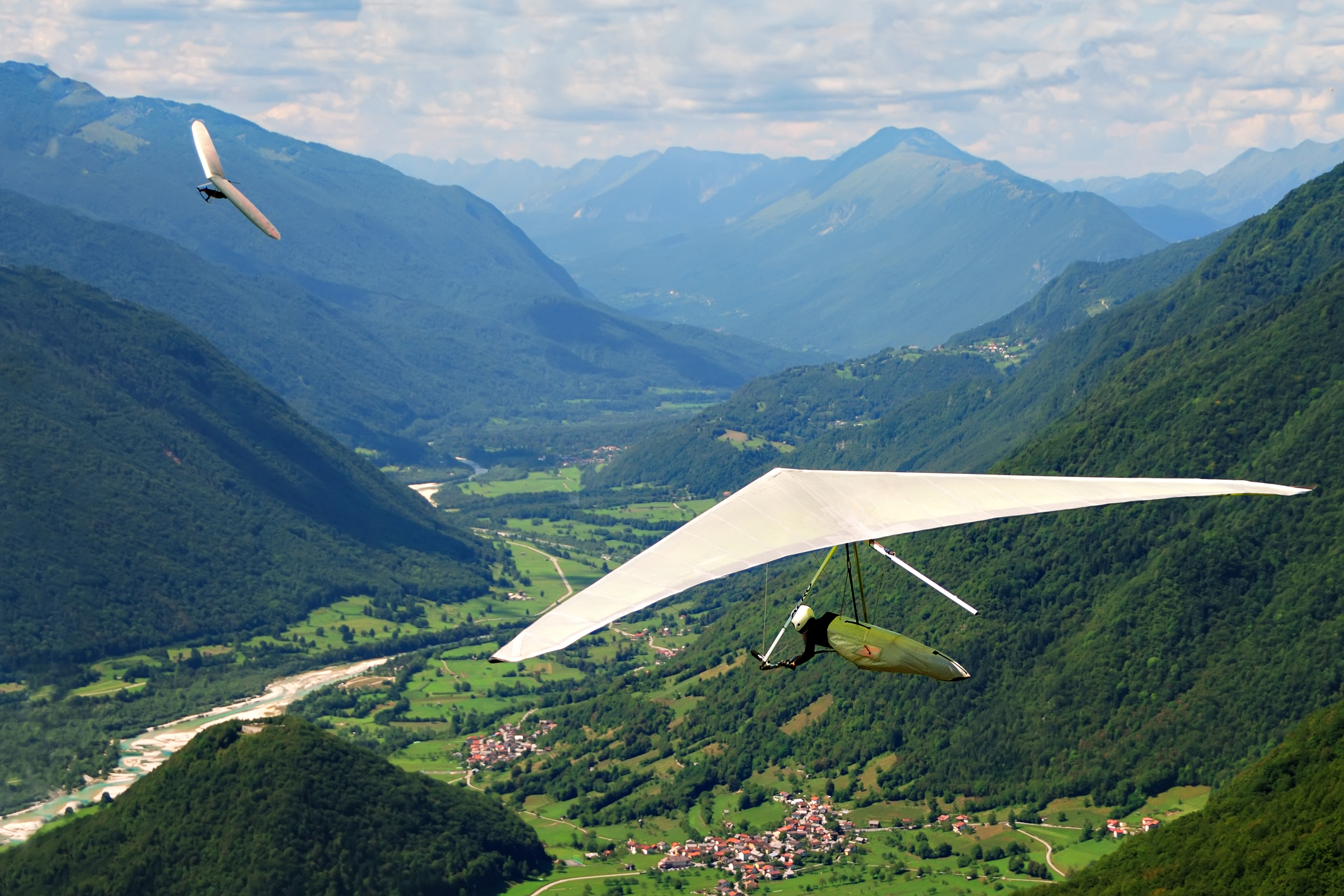 Person hang gliding through mountains. 
