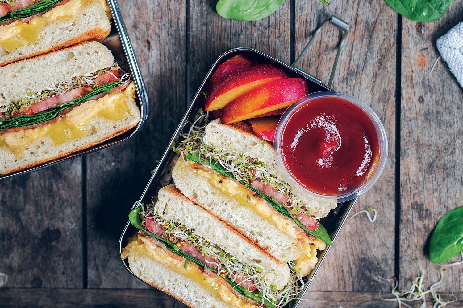 an egg sandwich and plum slices in a bento box