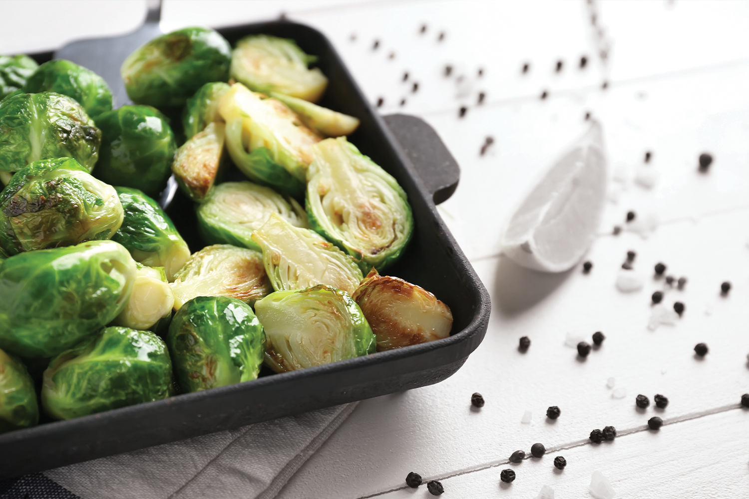 Roasted Brussels Sprouts in a black baking dish on a white table.