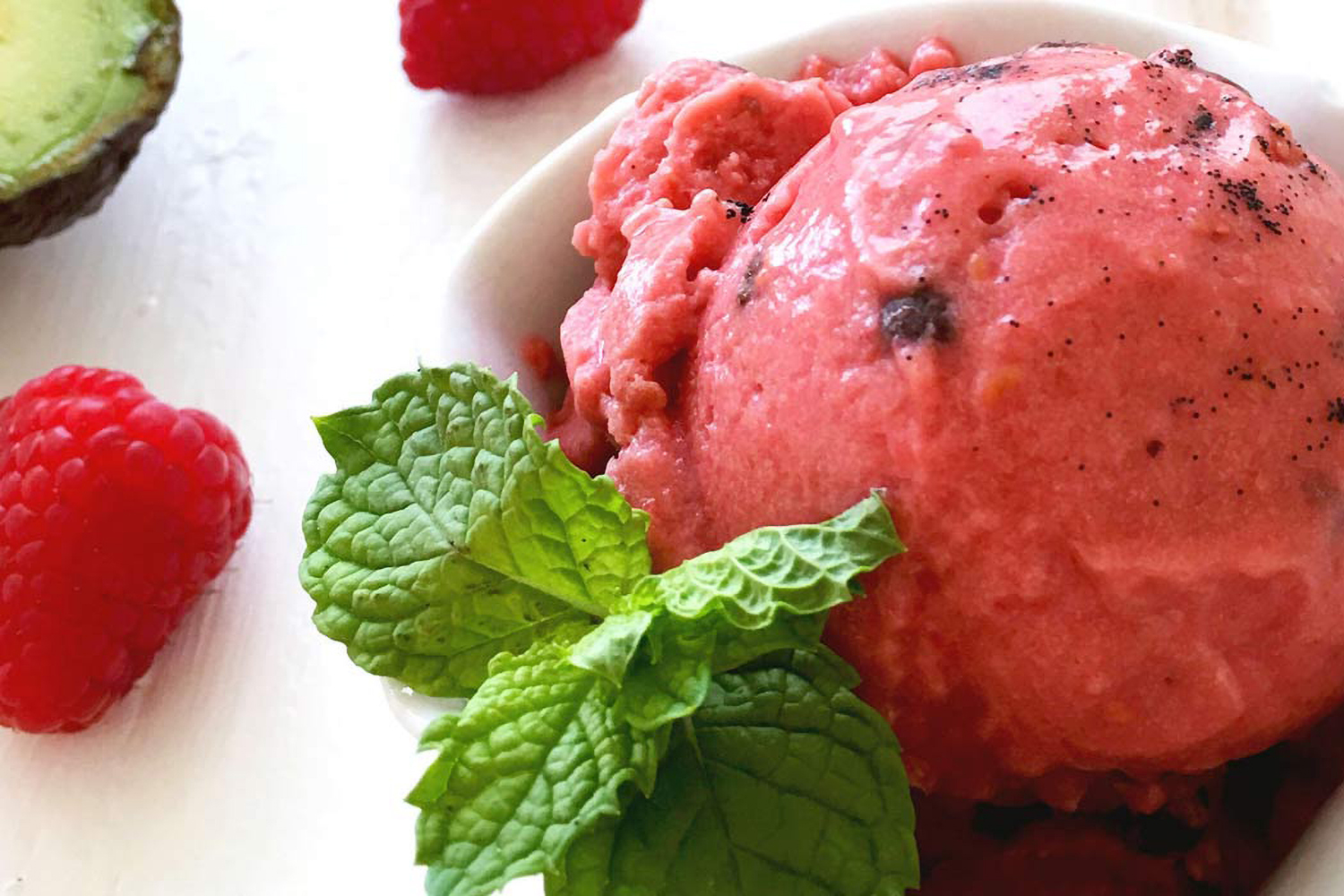 a dish of sorbet next to fresh avocado and raspberries