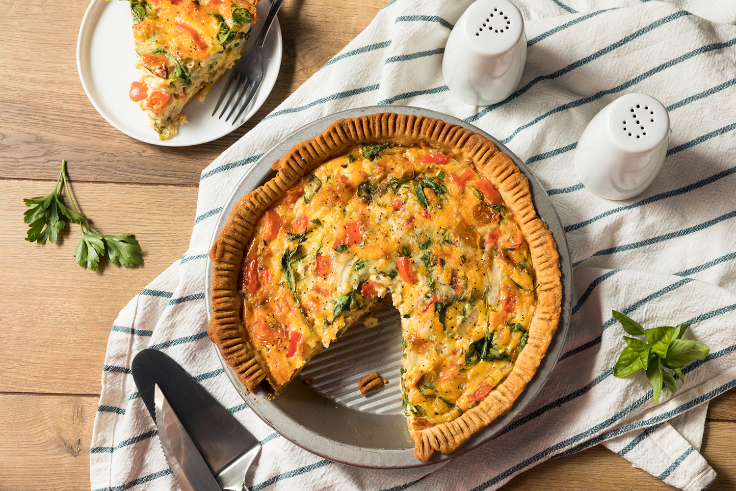 a pie tin of vegetable quiche missing a slice