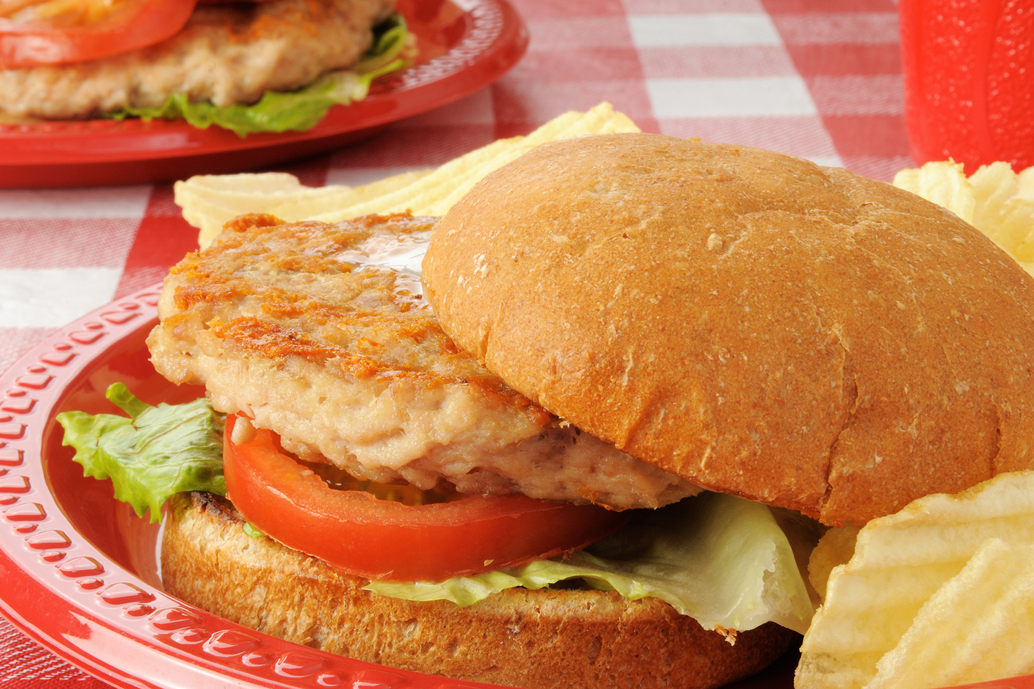 a ground chicken pattie on a bun with lettuce and tomato