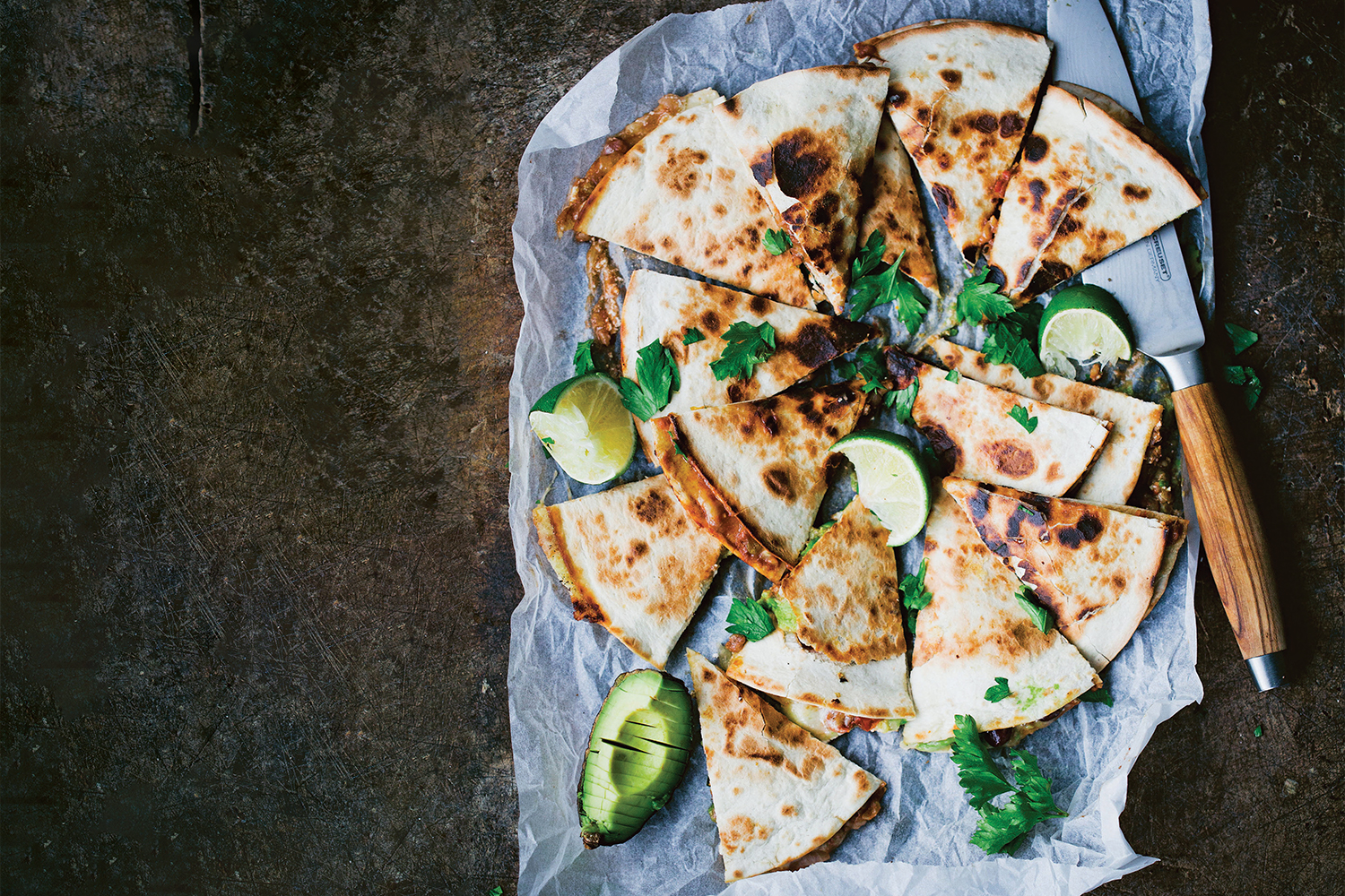 Top view of Portobello and Avocado Quesadillas on parchment paper cut into wedges to serve.