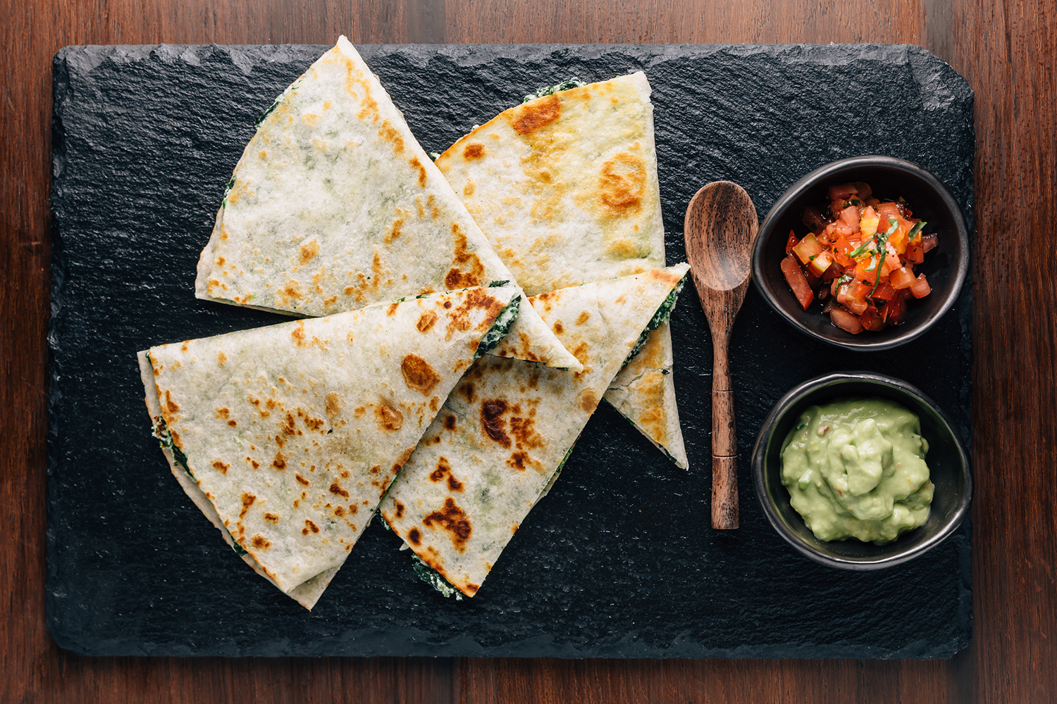 baked spinach quesadillas served on a slate with salsa