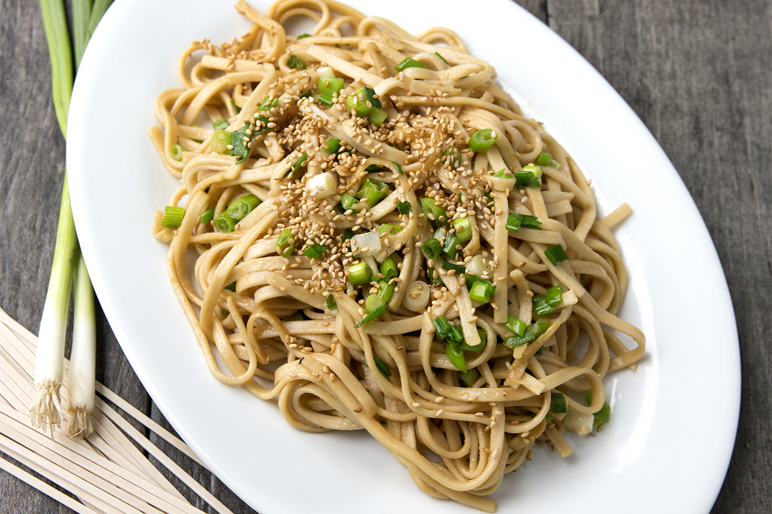a plate of stir-fried udon noodles with green onions