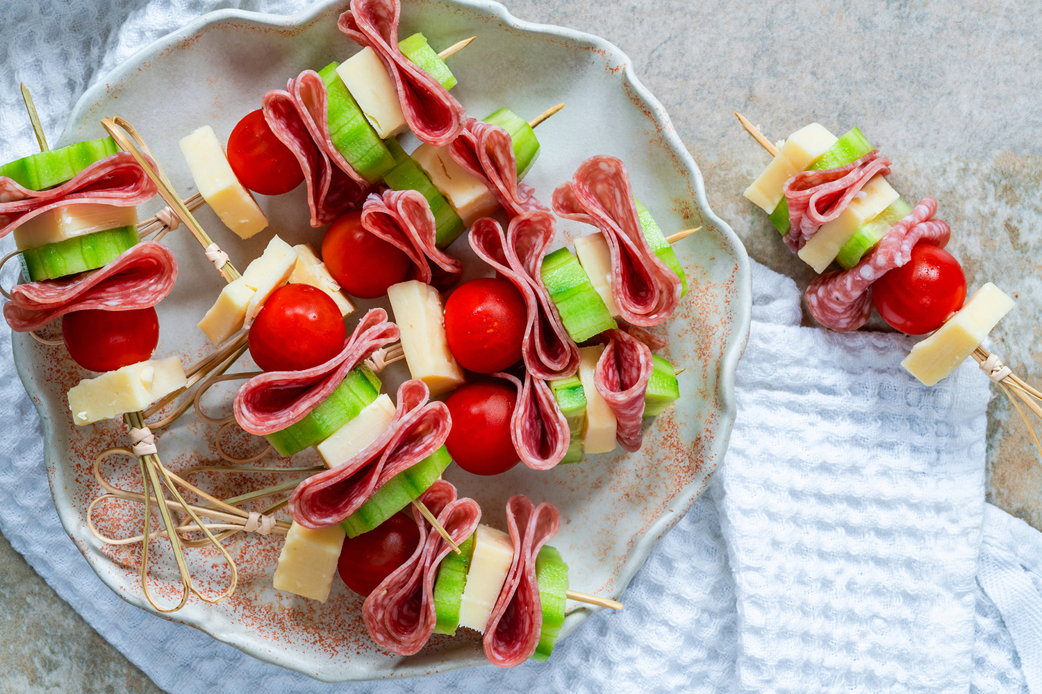 a plate of skewers with cheese and cherry tomato