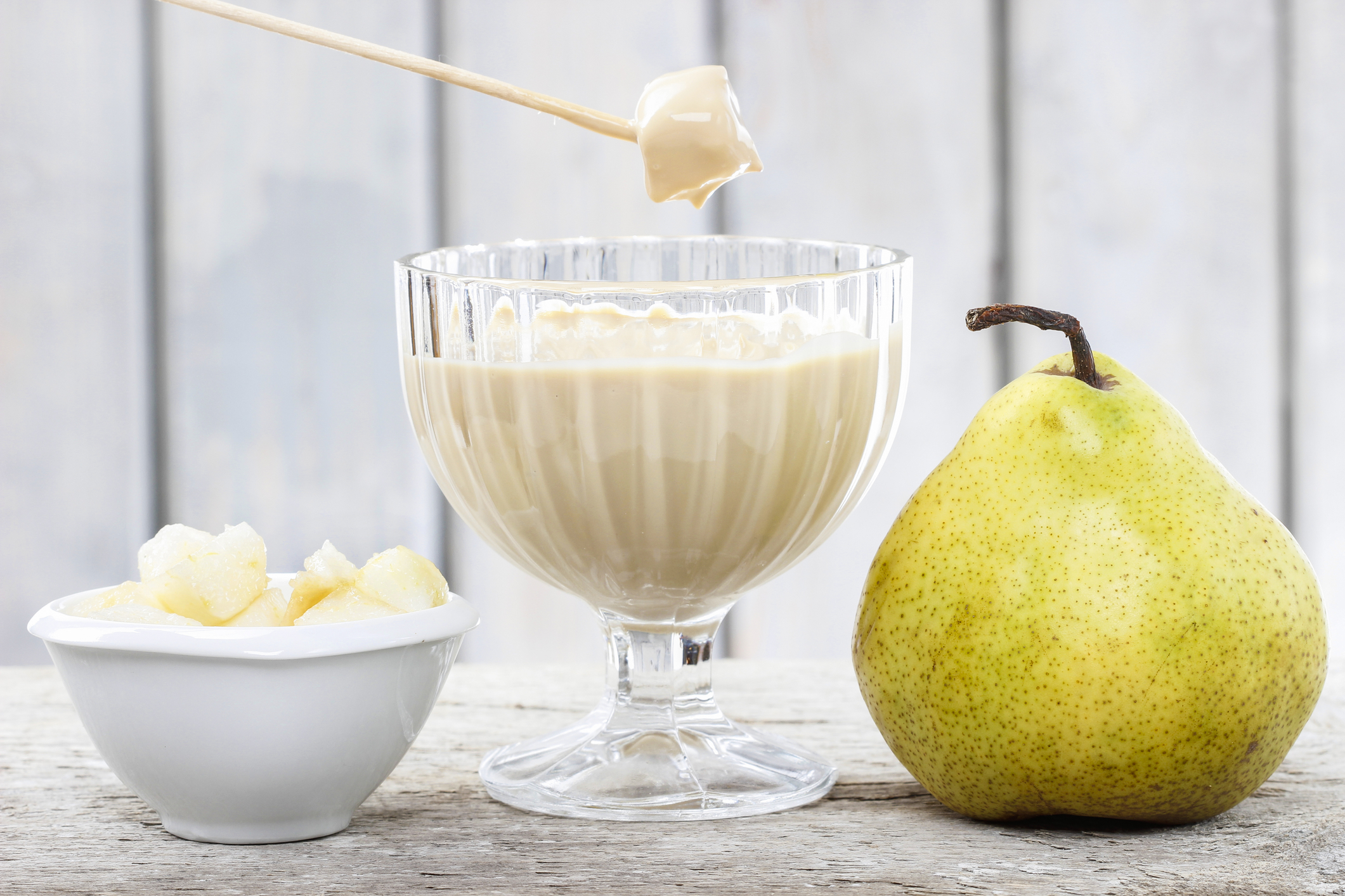 Chunks of pear being dipped into a goblet of Cinnamon Cheesecake Fondue. 