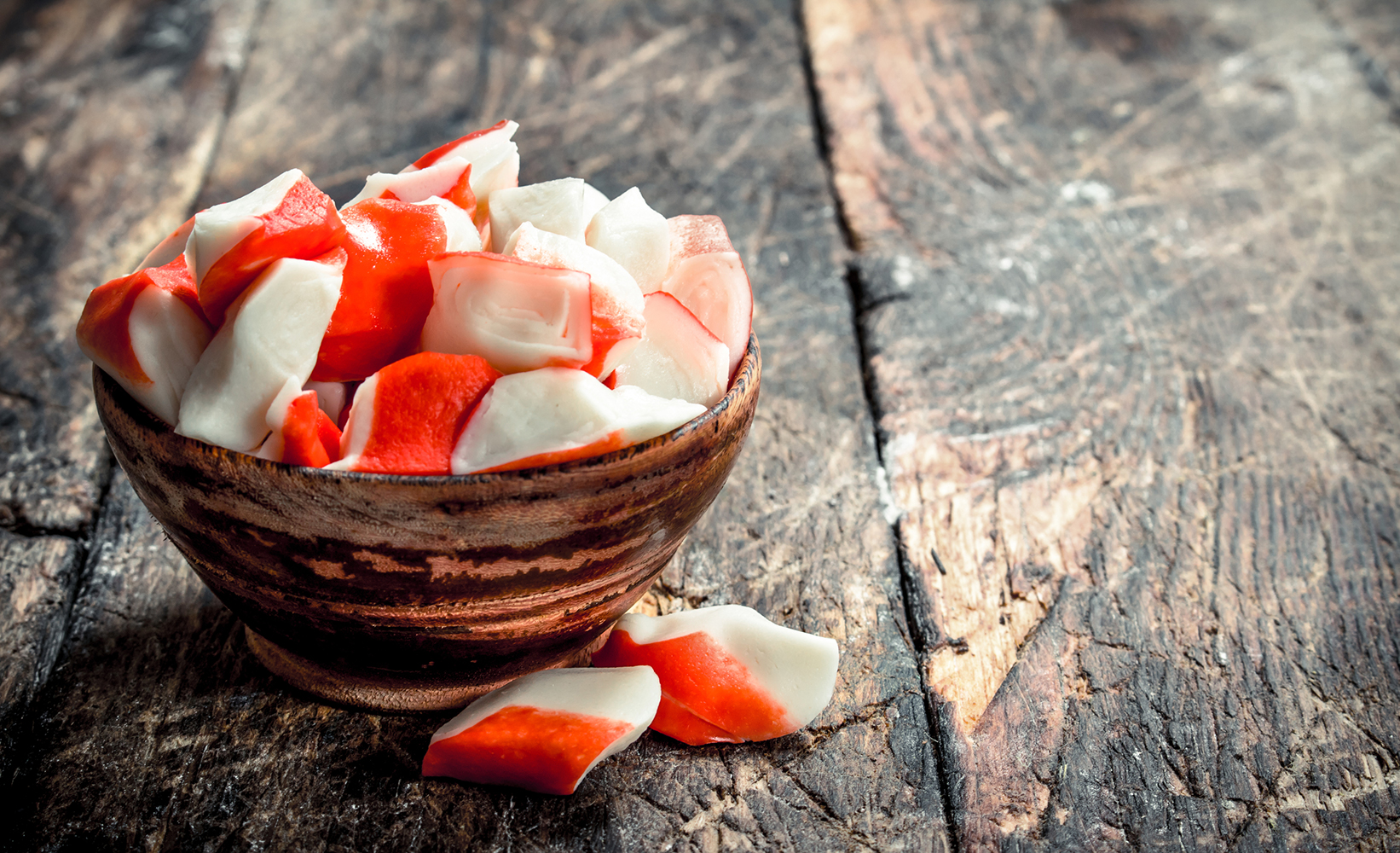 Crab meat in a bowl. On a wooden background.
