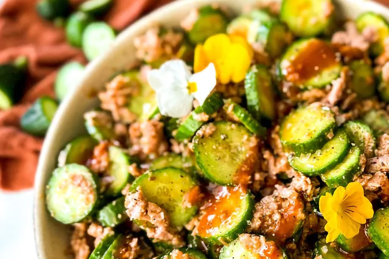 a bowl of tuna and cucumber with spicy sauce