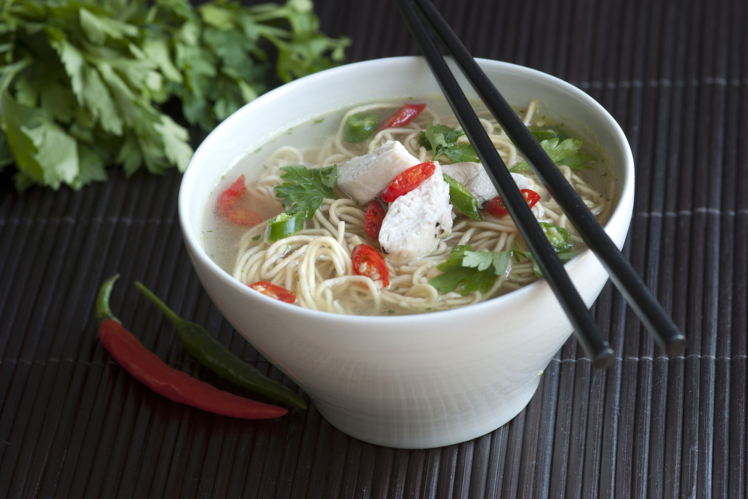 Bowl of asian chicken noodle soups with chopsticks.