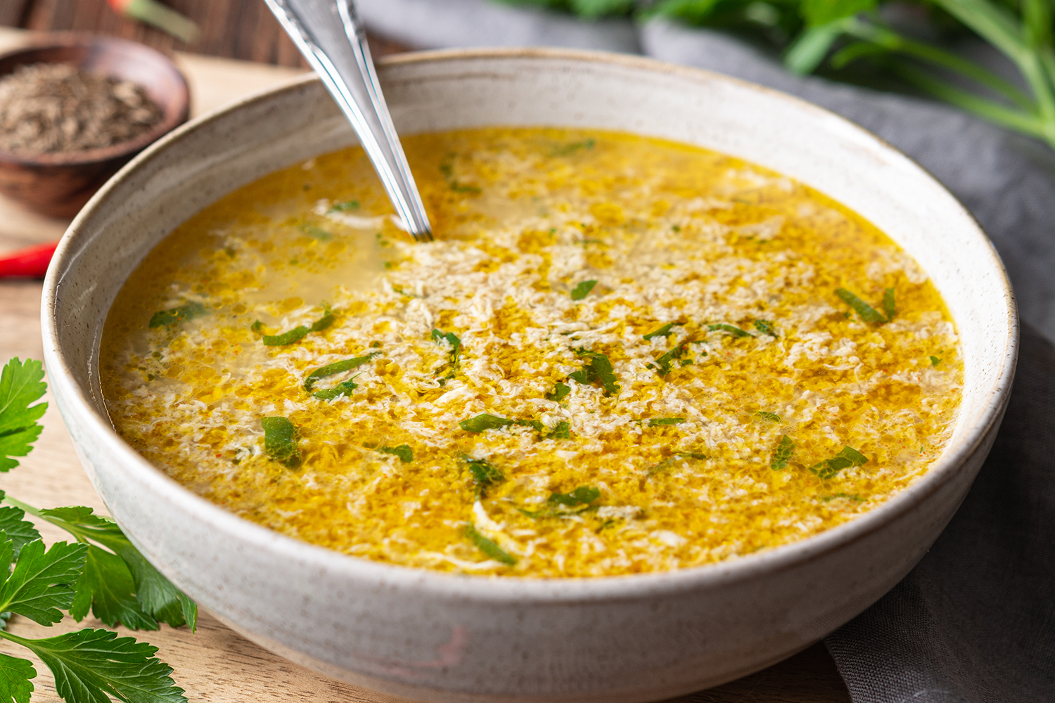 a bowl with broth, a dropped egg, and cilantro