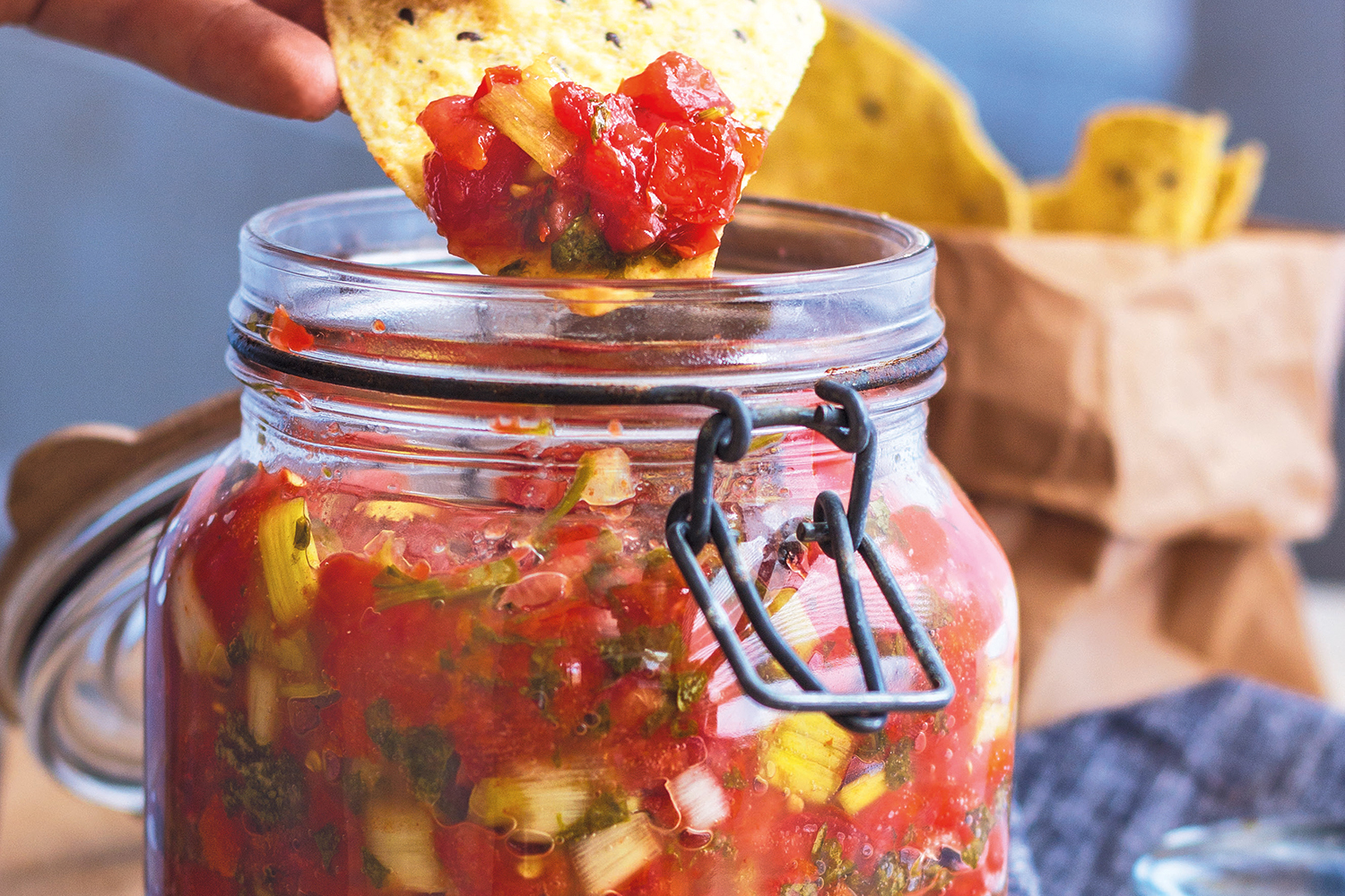 A tortilla chip dipped in a jar of fermented garden salsa
