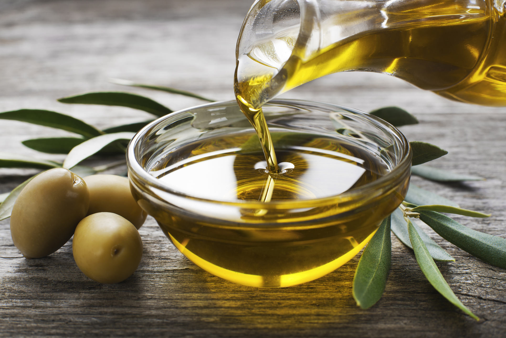 Olive oil bring poured into a glass bowl. 
