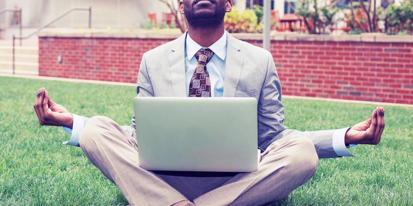 a businessman in partial lotus position with his laptop