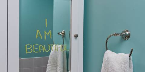 A bathroom mirror with "I am beautiful" written on it.