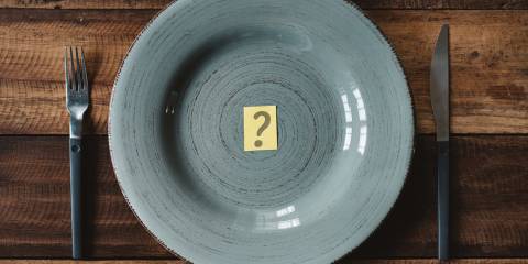 Top view of a table set with cutlery with question mark in a plate.