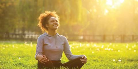 A woman sitting with legs crossed in a sunny field