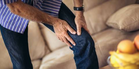a middle-aged man grabbing his bad knee in pain