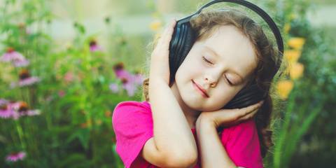 a little girl bopping to her headphones in a field of flowers