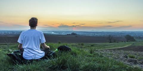 a man calmly watching the sun set over the water