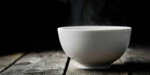 A white bowl of steaming bone broth.