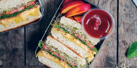 an egg sandwich and plum slices in a bento box