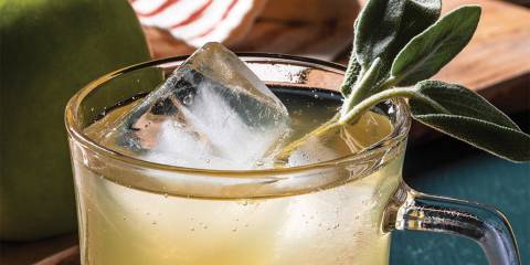 a glass of bubbly cider garnished with sage