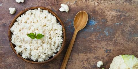 A wooden bowl filled with cauliflower rice.