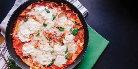 Top view of Veggie Skillet Lasagna, ready to serve from skillet, on a black background.