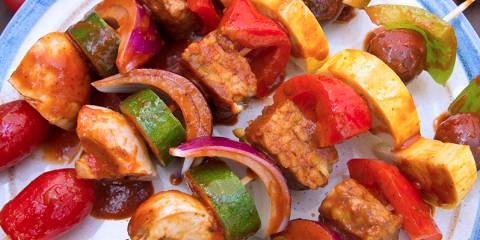 A plate of skewered vegetables and tempeh