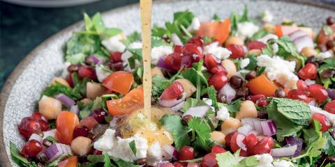 a bowl of lentils, vegetables, and herbs drizzled with dressing