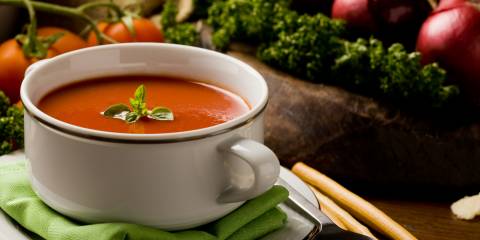 a bowl of soup surrounded by fresh vegetables