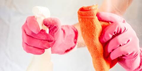 Hands with rag and spray bottle cleaning glass.