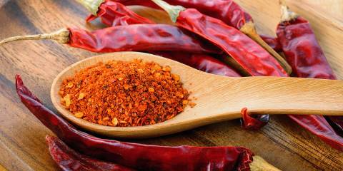 cayenne peppers and a spoon of dried cayenne powder