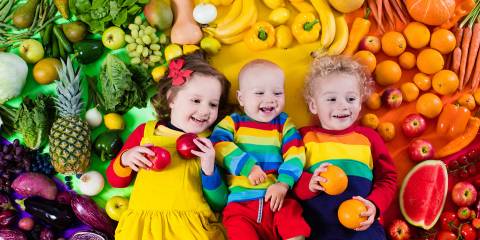 Young cute siblings surrounded by a rainbow of healthy produce