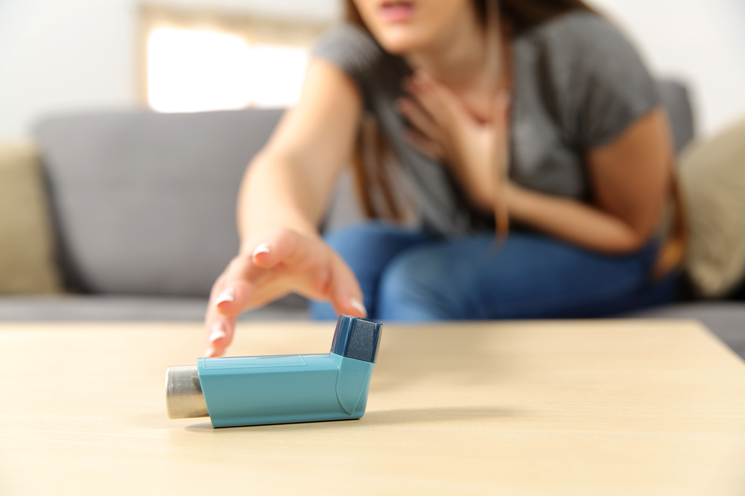 a woman having an asthma attack reaching for her rescue inhaler