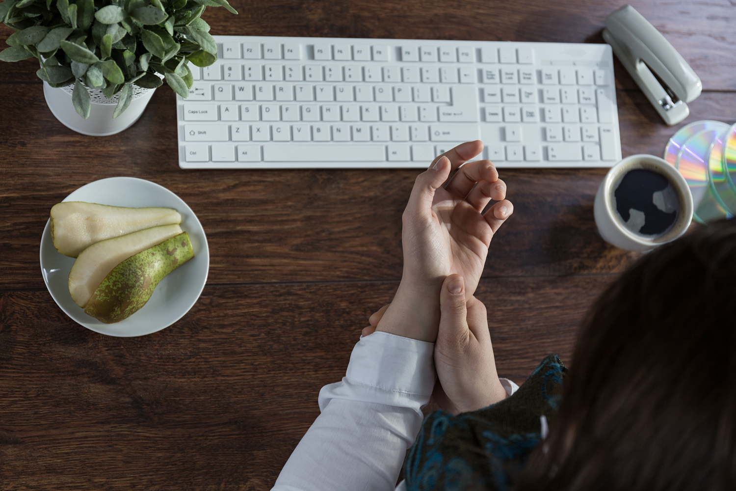 A woman massaging her inflamed wrist in front of a keyboard